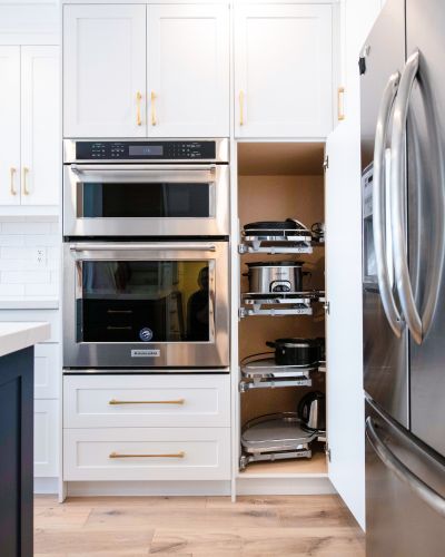 Kitchen renovation in Richmond Hill with built-in double wall oven, pull-out pantry storage, white cabinets, and gold hardware by Smart Renovations